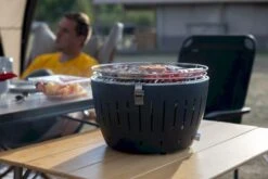 LotusGrill XL Hybrid Houtskoolbarbecue - Rood 22 LotusGrill XL Hybrid Houtskoolbarbecue - Rood -Buiten Kamperen Winkel lotusgrill in gebruik met toppy shirtje 2